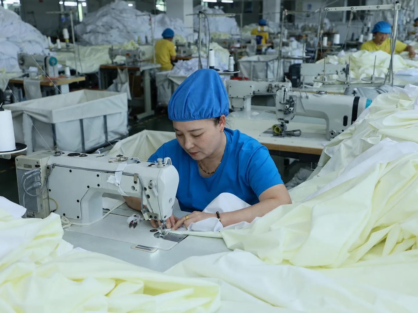 Blue-uniform sewing operator completing bedding construction
