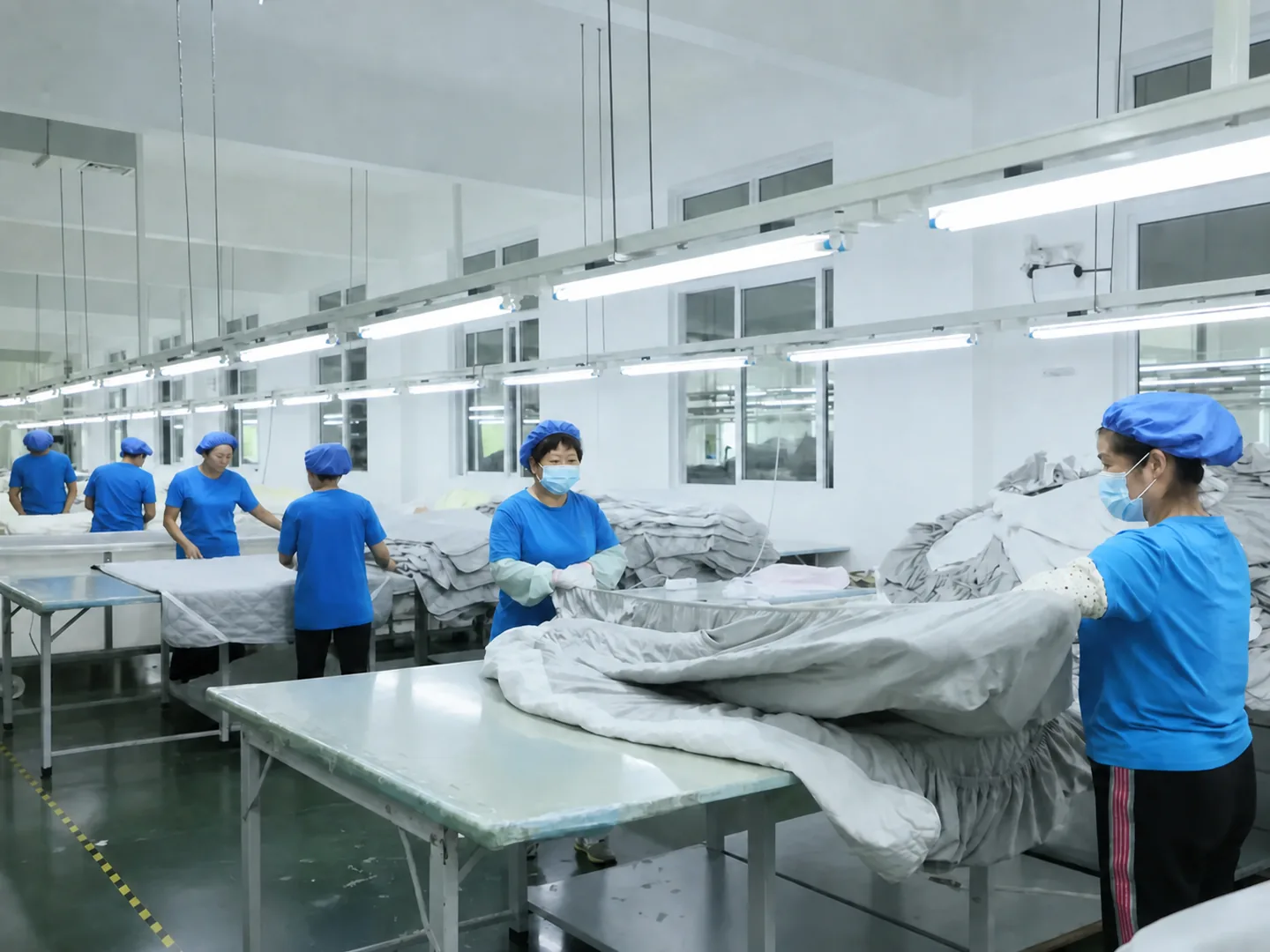 Blue-uniform production team coordinating large bedding components