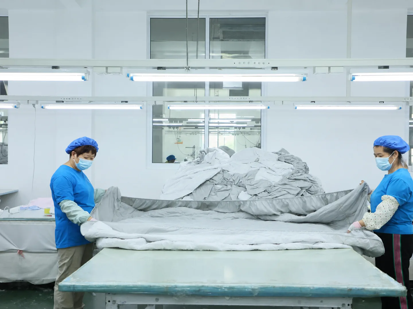 Blue-uniform production team organizing prepared bedding components