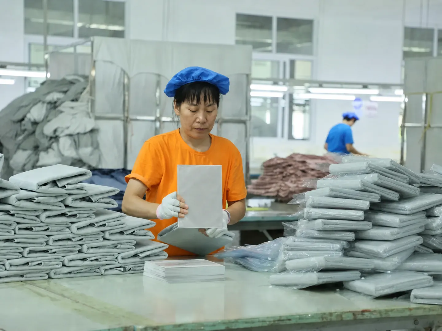 Orange-uniform packing operator sorting packaged bedding for order handling