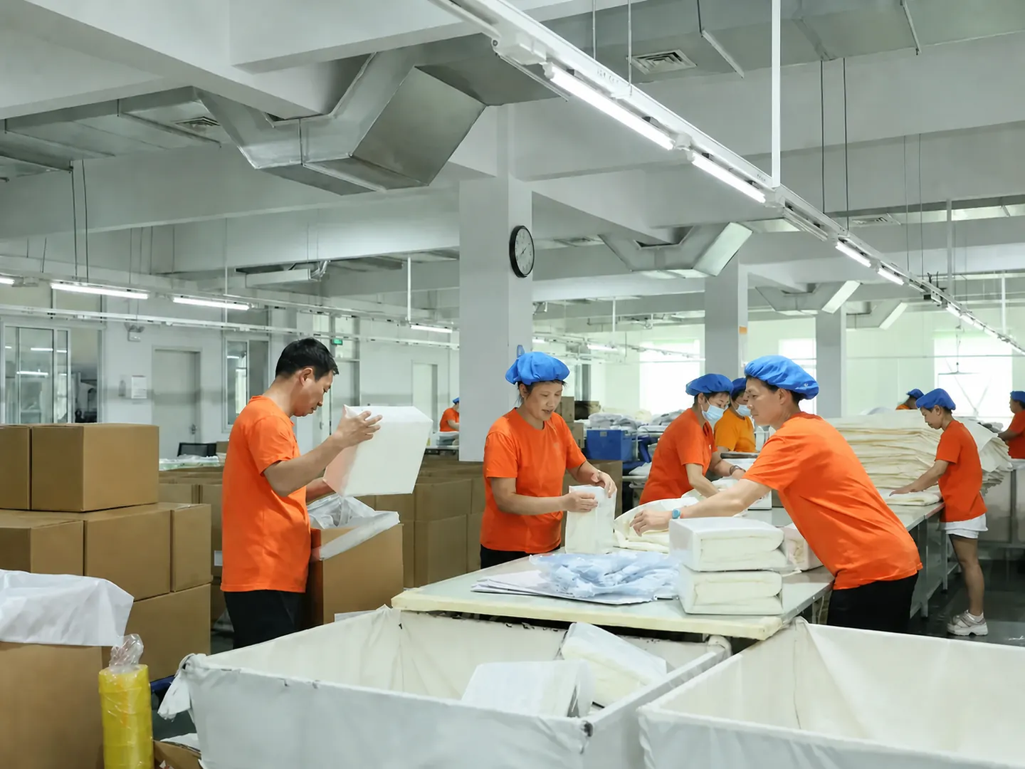 Orange-uniform packing team organizing finished bedding products