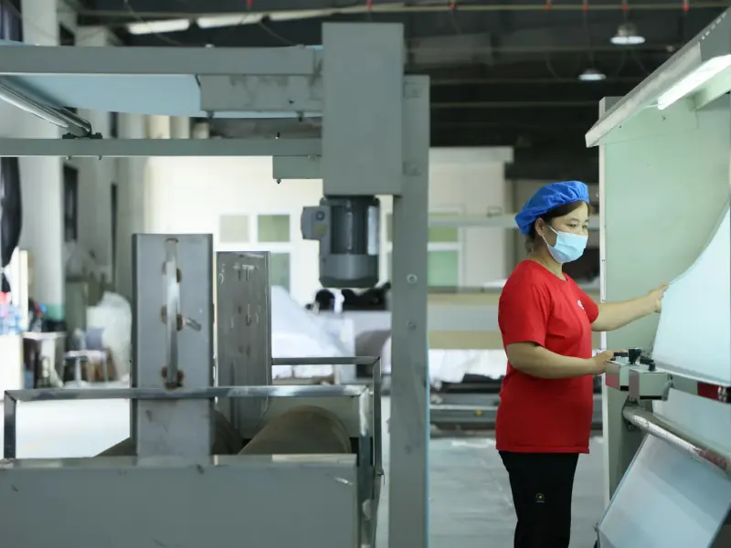Incoming material QC personnel checking raw fabric at an illuminated inspection surface