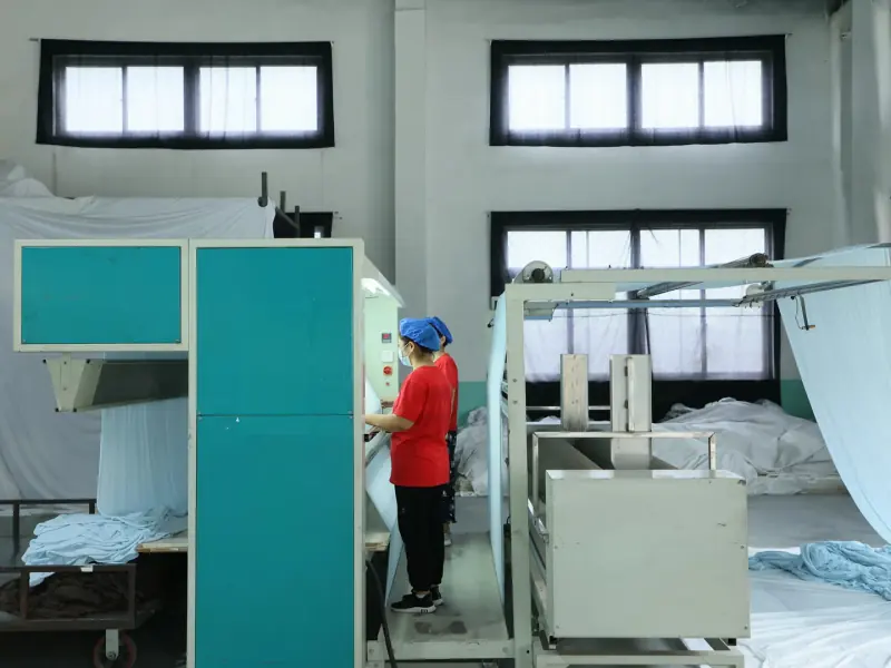 Incoming material QC personnel operating fabric inspection equipment for a batch-based sample review