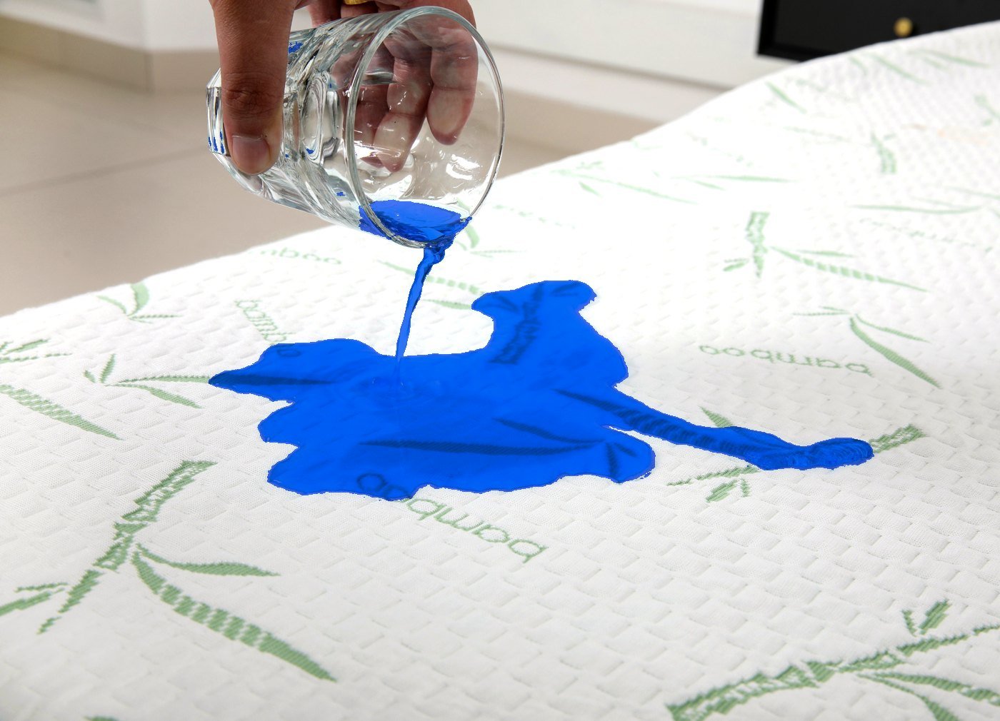 Blue water poured onto a Dreamelix bamboo mattress protector to demonstrate waterproof performance